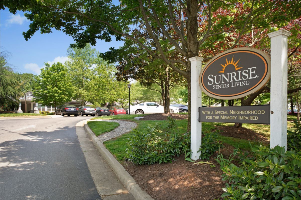 Entrance to Sunrise Senior Living community with surrounding trees and parking lot.