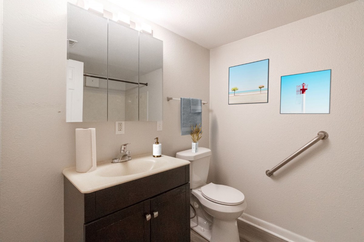 A modern bathroom with a vanity, sink, mirror, and toilet.