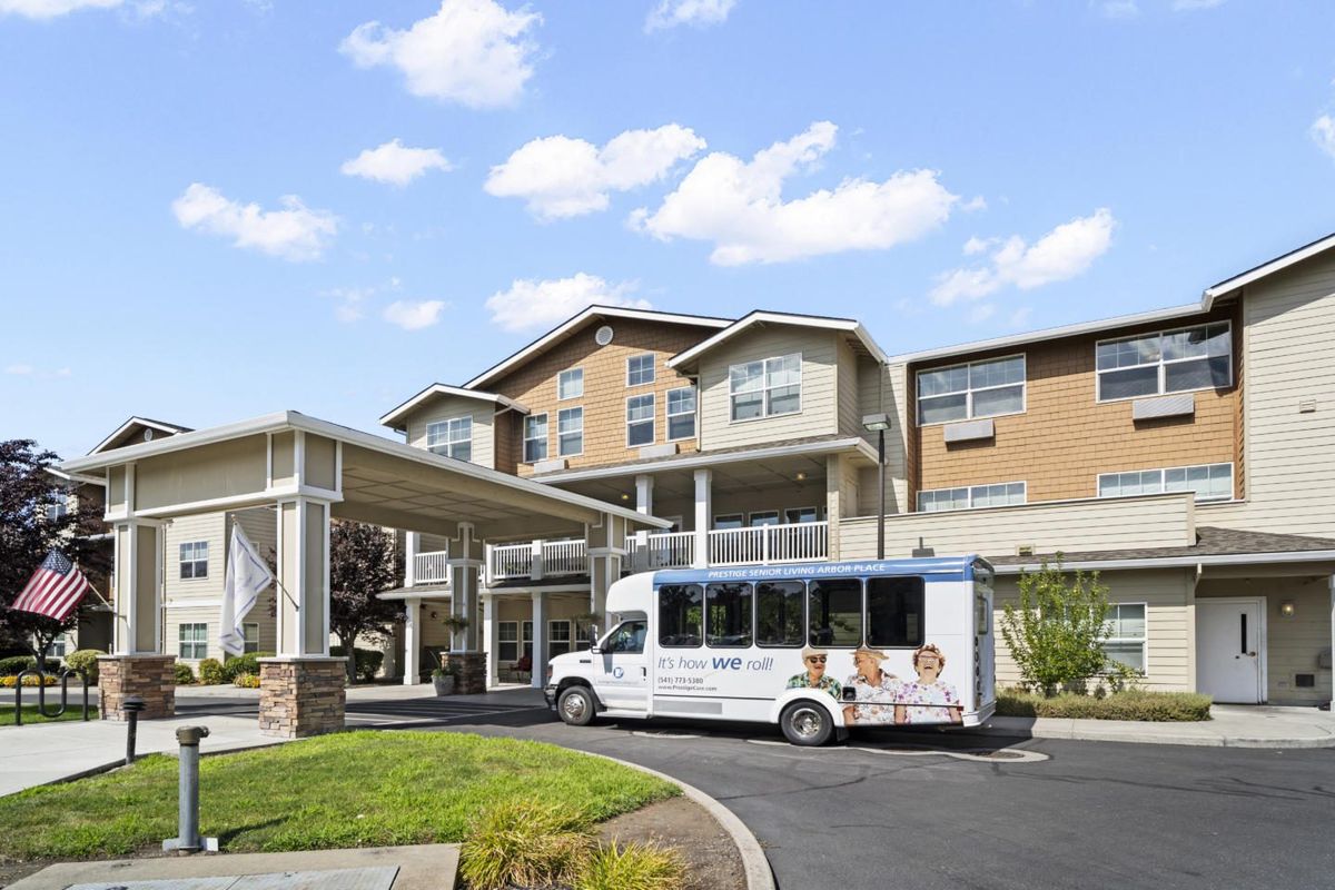 A modern residential building with a shuttle bus parked at the entrance.