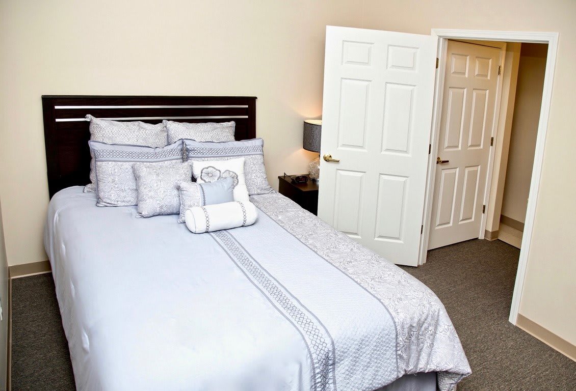 A neatly arranged bedroom with a well-made bed and decorative pillows.