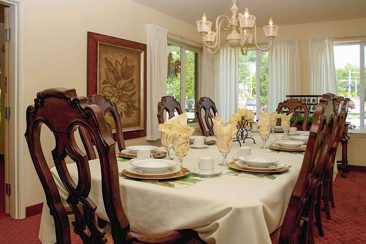 An elegantly set dining room table with a chandelier overhead.