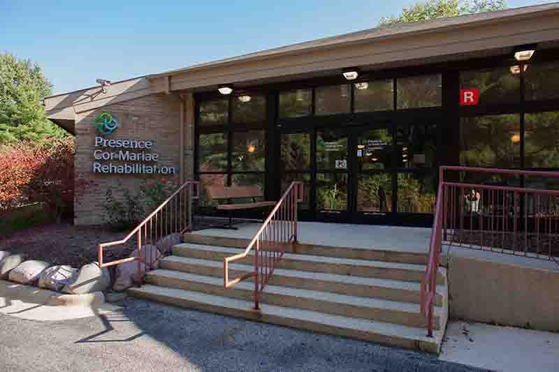 Entrance of a facility with stairs leading to glass doors.