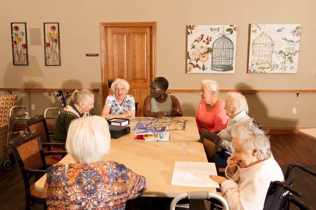 A diverse group of seniors engaged in a meeting or discussion around a table indoors.