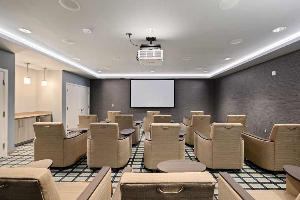 A modern conference room with comfortable seating, equipped with a projector and screen.