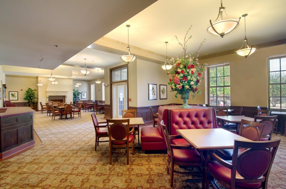A spacious lobby area with elegant furnishings, featuring a large table with red cushioned seating and stylish lighting.