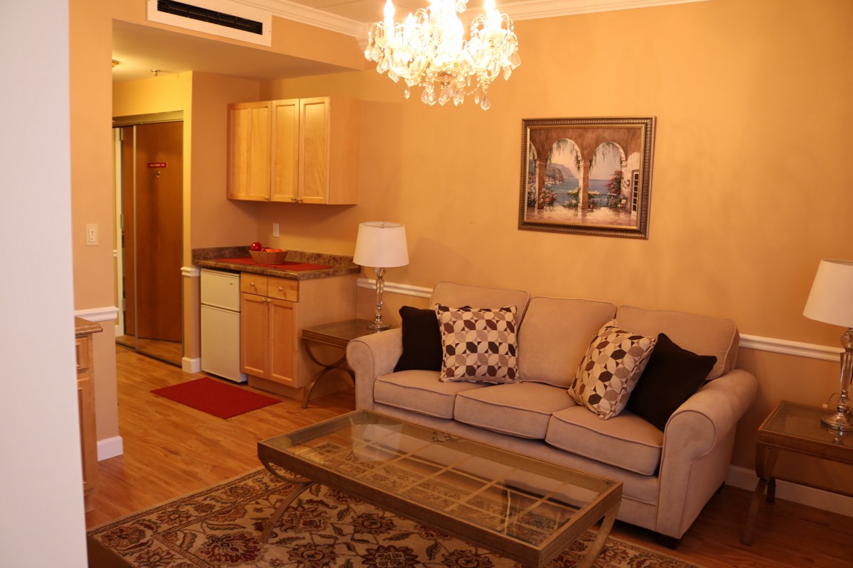 A cozy living room with a sofa, coffee table, and a chandelier overhead.