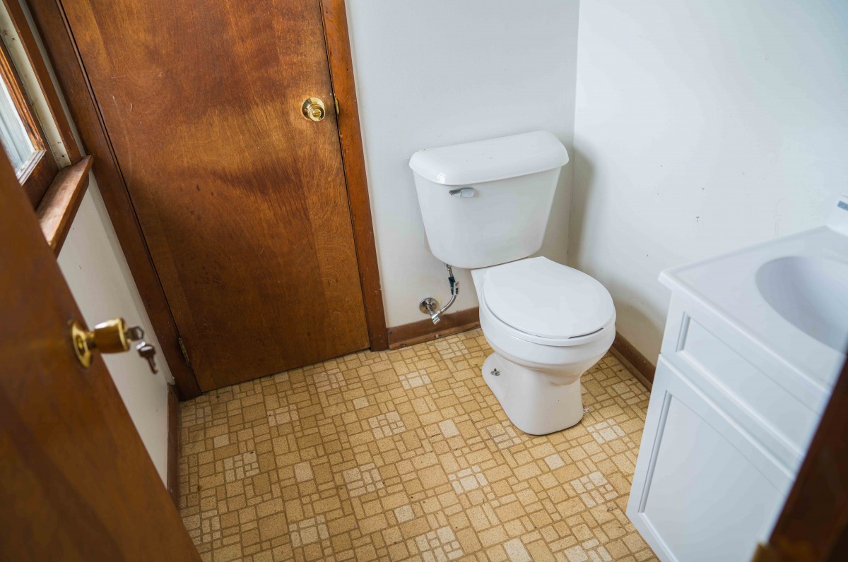 A bathroom with a toilet and vintage patterned flooring.