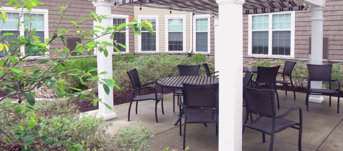 An outdoor patio area with a table and chairs under a pergola.