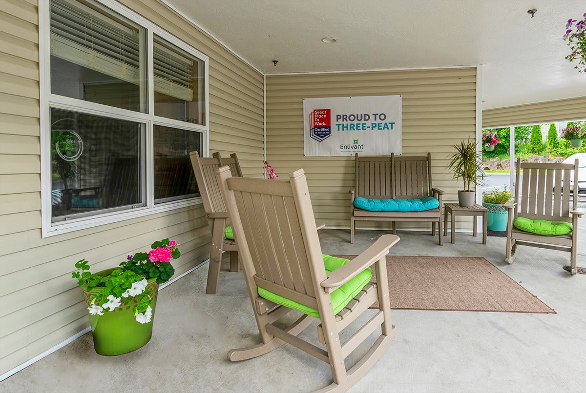 A cozy porch with rocking chairs and potted plants, featuring a welcoming sign.
