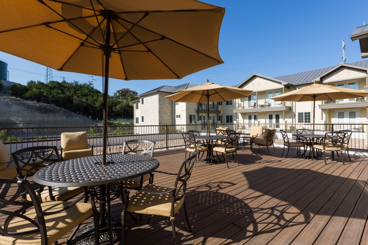A spacious outdoor patio with tables, chairs, and umbrellas on a sunny day.