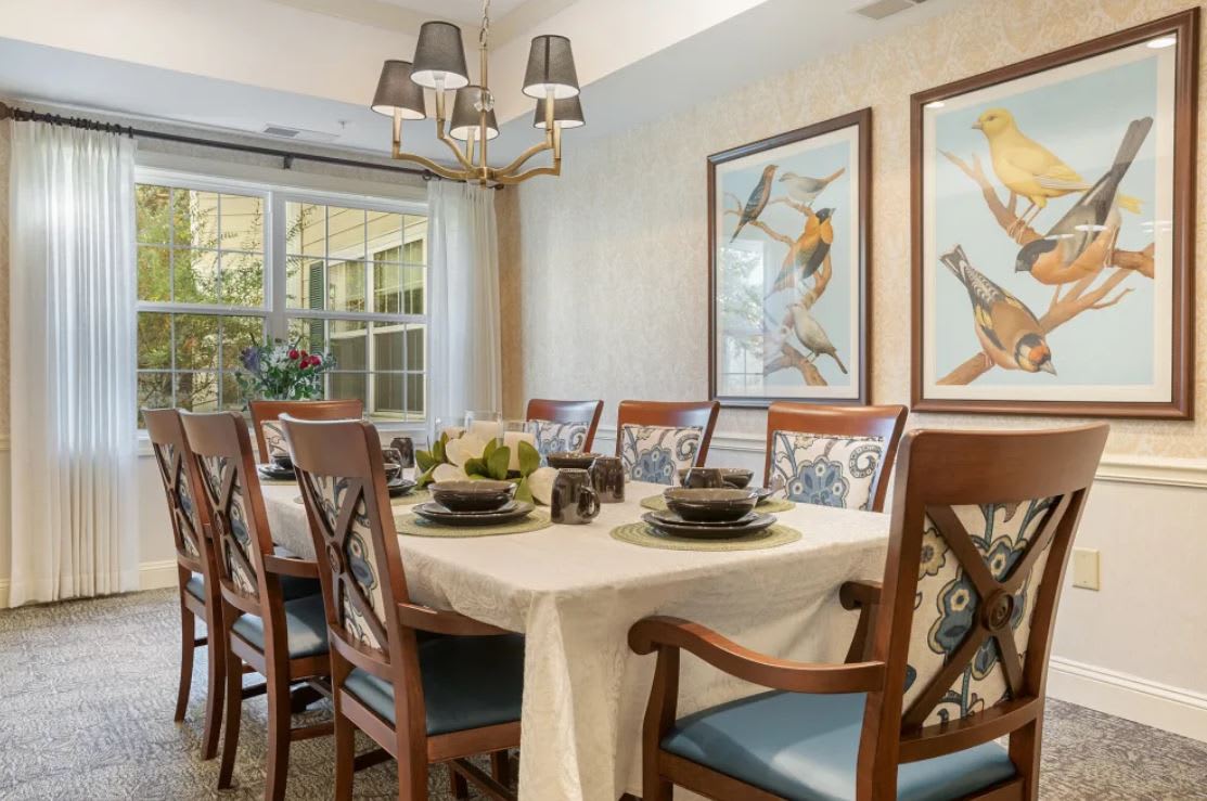 A well-decorated dining room featuring a set table, elegant chairs, and framed artwork on the walls.
