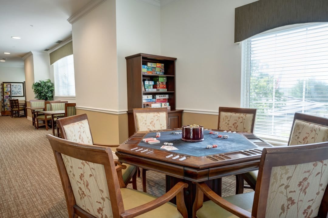 A cozy game room with a card table and board games on the shelves.