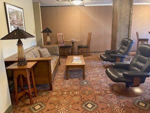 A cozy living room with a sofa, armchairs, and a coffee table on a patterned carpet.