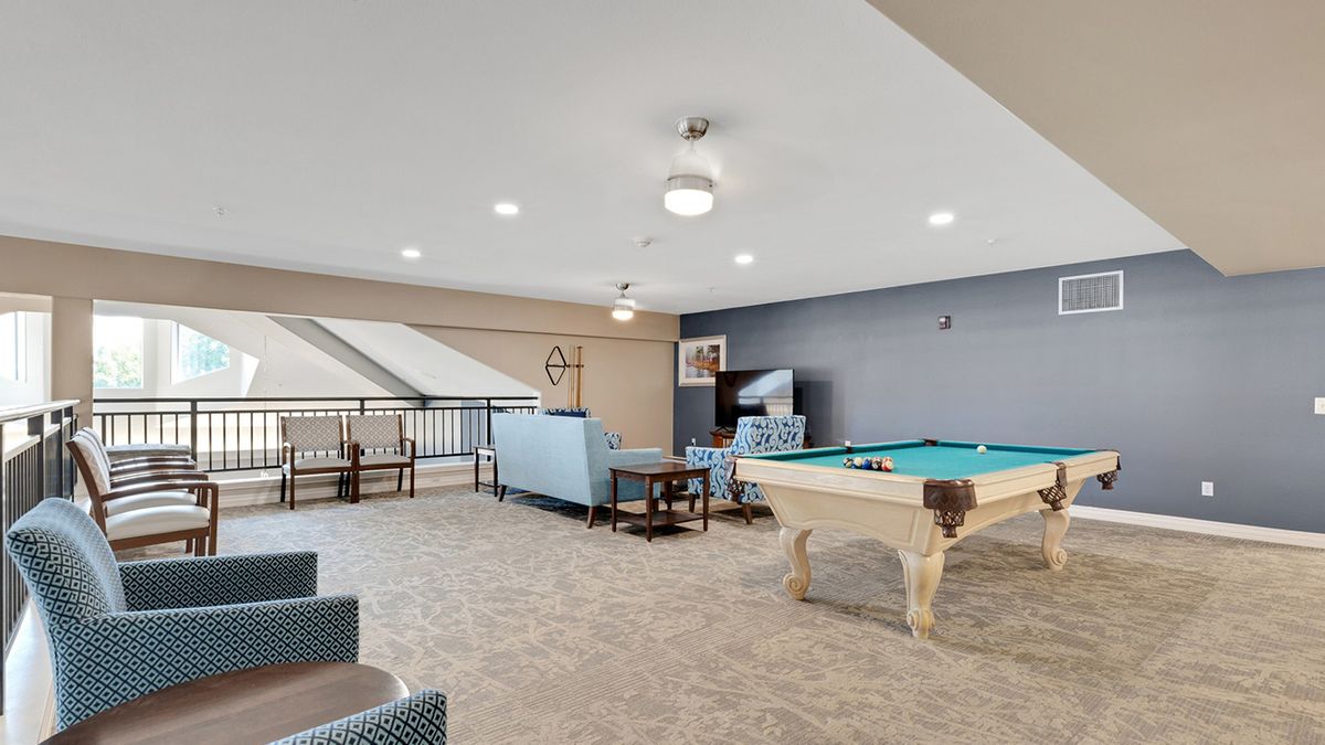 A modern game room featuring a pool table and comfortable seating.