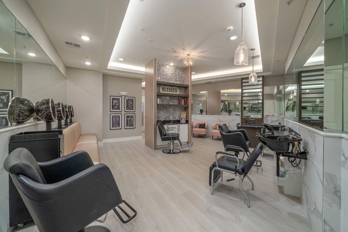 A modern beauty salon interior with styling chairs, mirrors, and bright lighting.