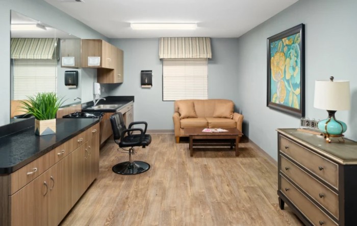 A neatly organized office space with a desk, chair, and sofa, featuring artwork on the wall.