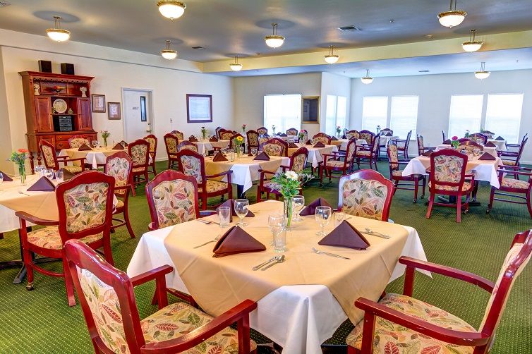 A well-arranged dining room featuring neatly set tables with floral chairs, ready for guests.