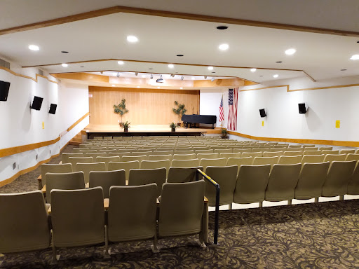 A spacious auditorium featuring seating arrangements, a stage, and decorative elements.