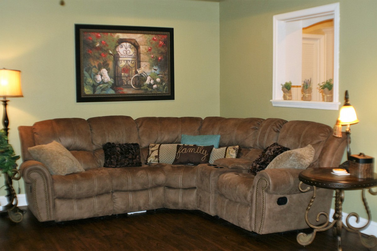 A cozy living room with a large sectional sofa, adorned with various cushions, and a framed artwork on the wall.