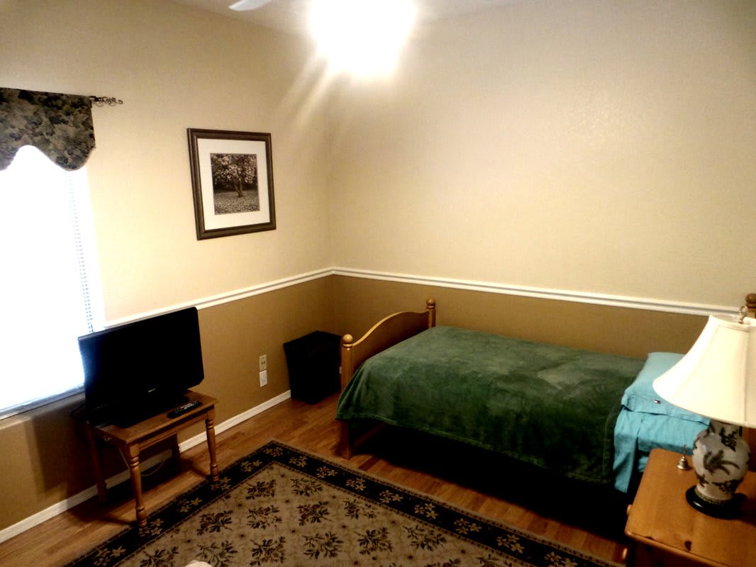 A minimalist bedroom with a single bed, television, and framed picture.