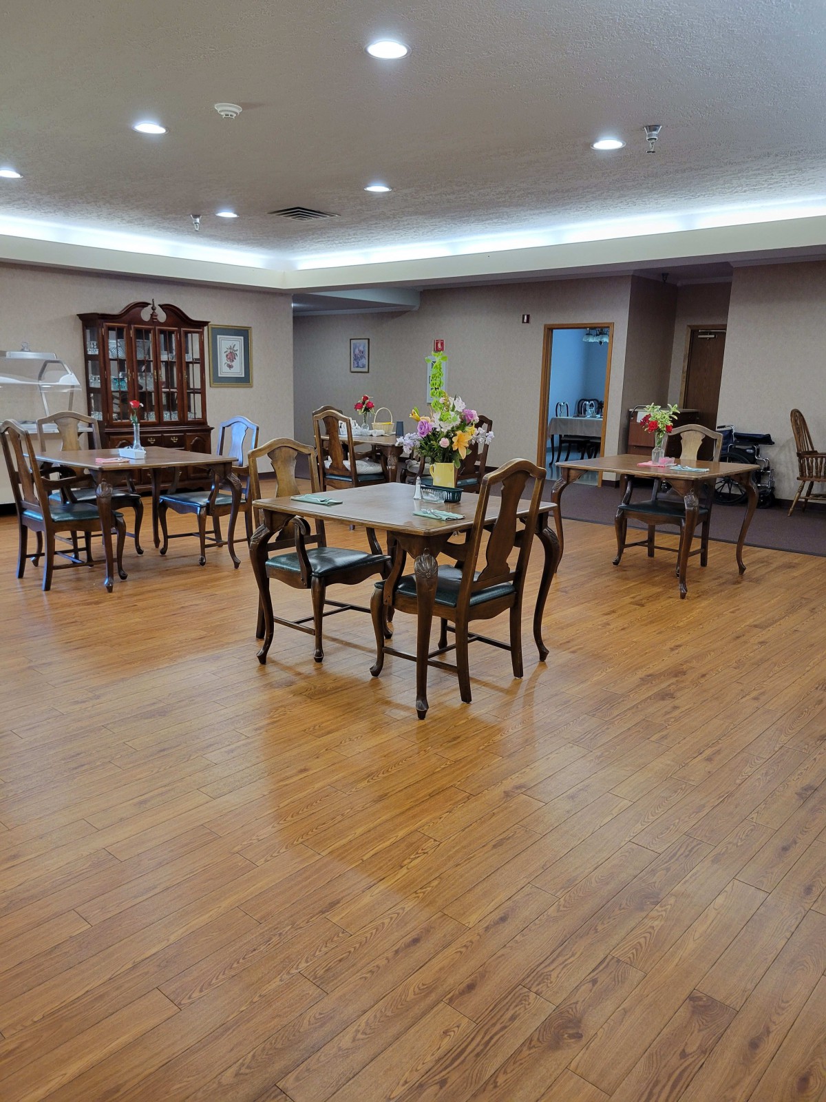 A spacious dining room with wooden floors and elegant furniture arranged neatly.