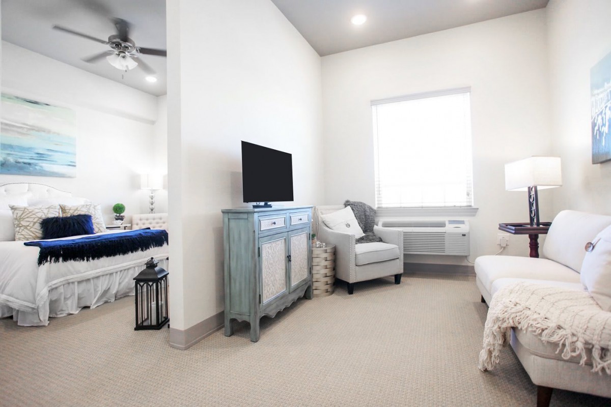 A modern living space with a TV, chair, and light color scheme.