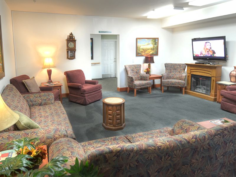 A cozy living room with sofas, chairs, a television, and warm lighting.