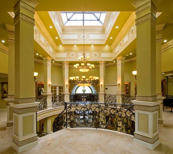 A grand interior space featuring a skylight, elegant columns, and ornate chandeliers.