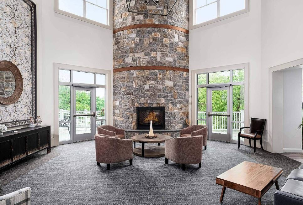 A modern living room with a tall stone fireplace and comfortable seating.