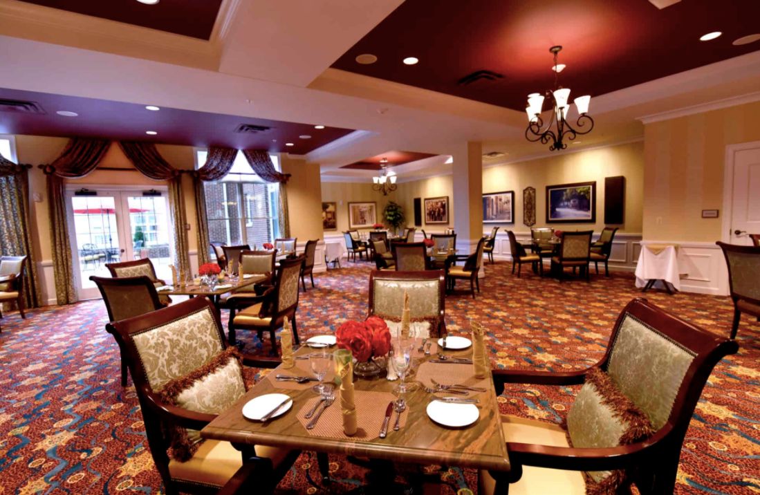 An elegant dining room with neatly arranged tables and chairs, featuring warm lighting and tasteful decor.