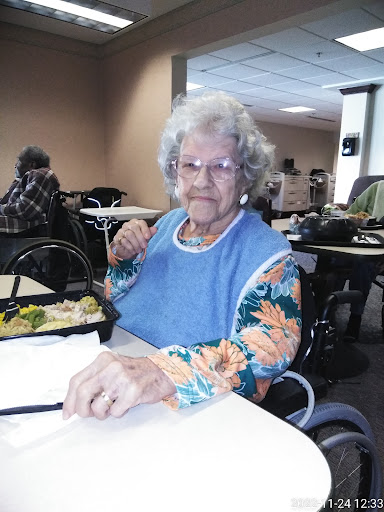An elderly woman enjoying her meal in a cozy dining space.