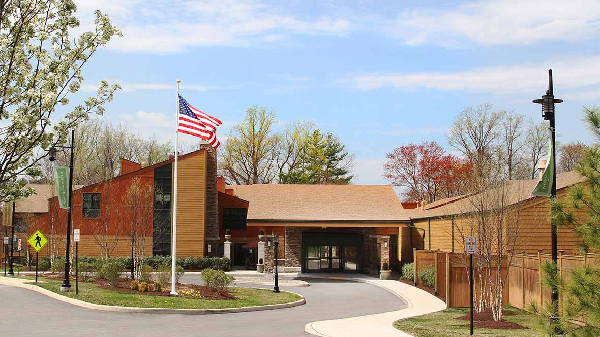 Entrance of a building with an American flag and surrounding trees.