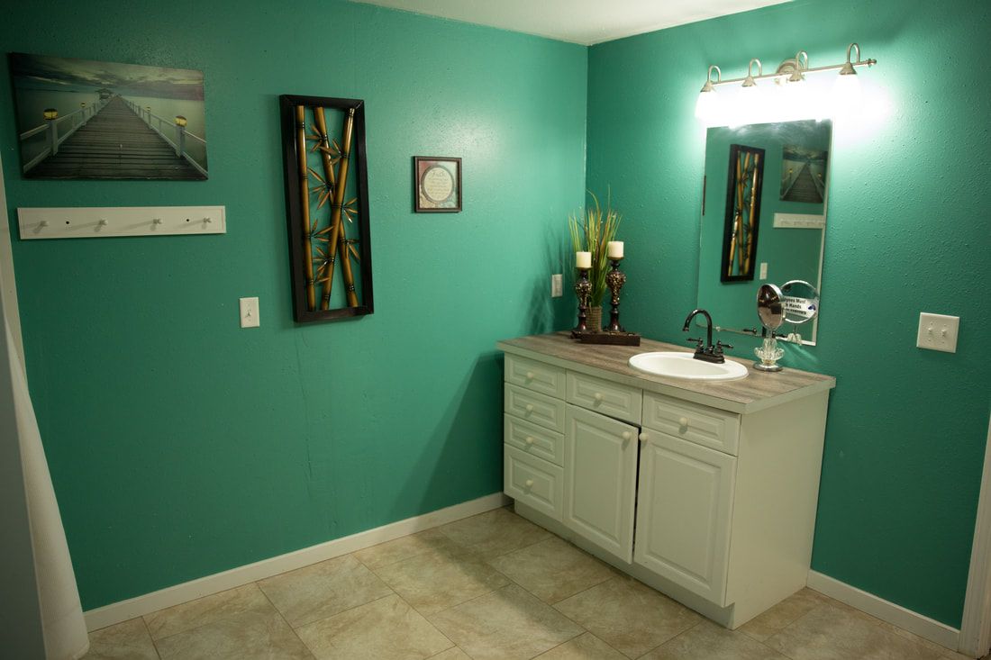 A bathroom featuring turquoise walls, a vanity with a sink, and decorative wall art.