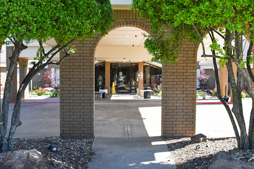 An inviting entrance framed by lush greenery, leading into a well-lit lobby.