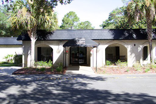 A serene view of a building entrance framed by lush greenery and shadows.