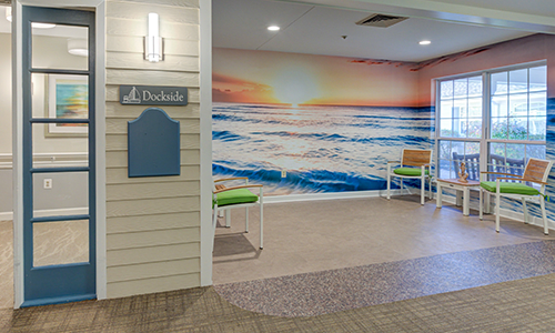 A welcoming lobby area featuring a stunning beach sunset mural with seating arrangements.
