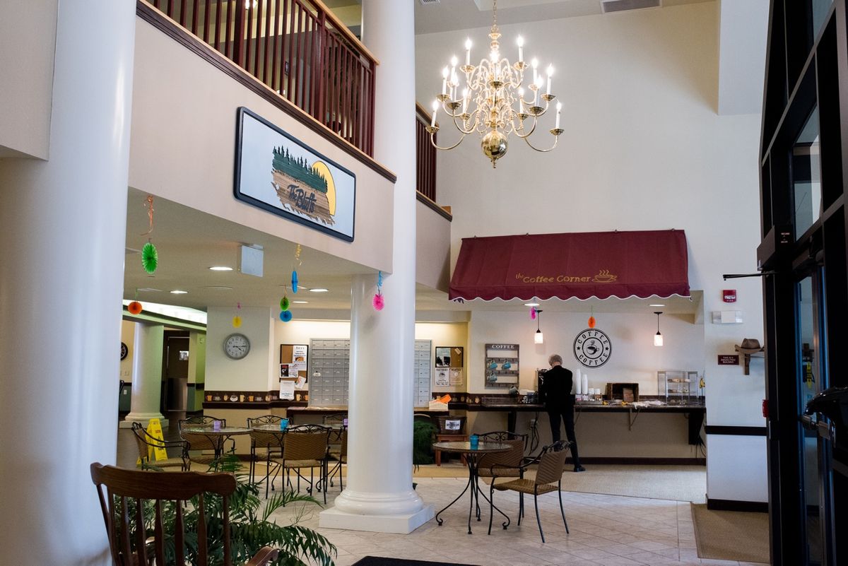 A spacious lobby with a seating area, chandelier, and a cafe counter.