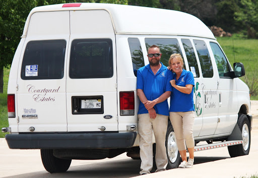 A cheerful team of staff members poses beside their transportation van.