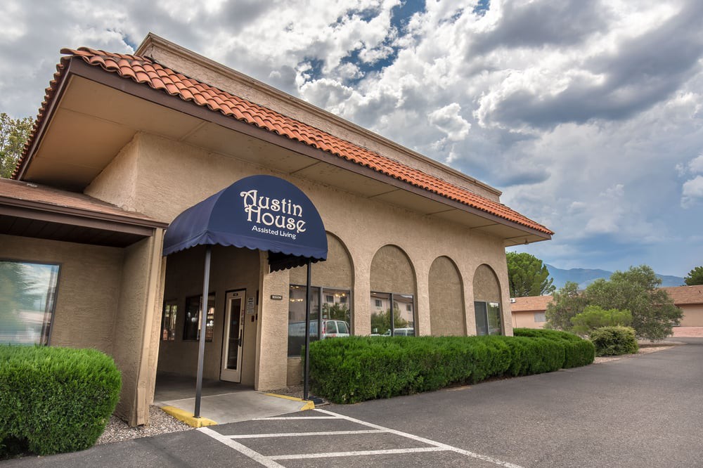 The exterior of a restaurant building with a blue awning under a cloudy sky.