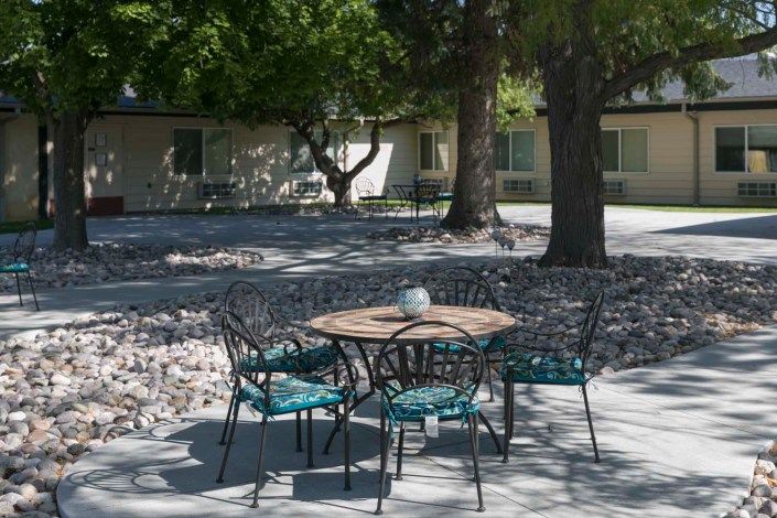 A peaceful outdoor patio area with a table and four chairs, surrounded by trees.