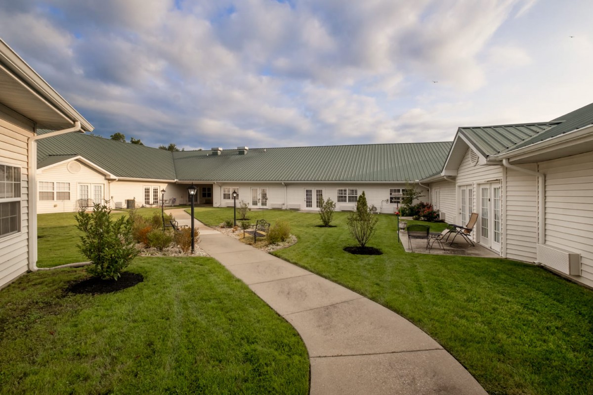 A building with a green lawn and pathway under a cloudy sky.