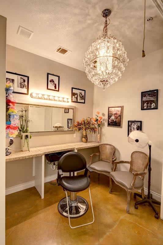 A cozy dressing room featuring a vanity with a mirror, elegant lighting, and vintage decor.