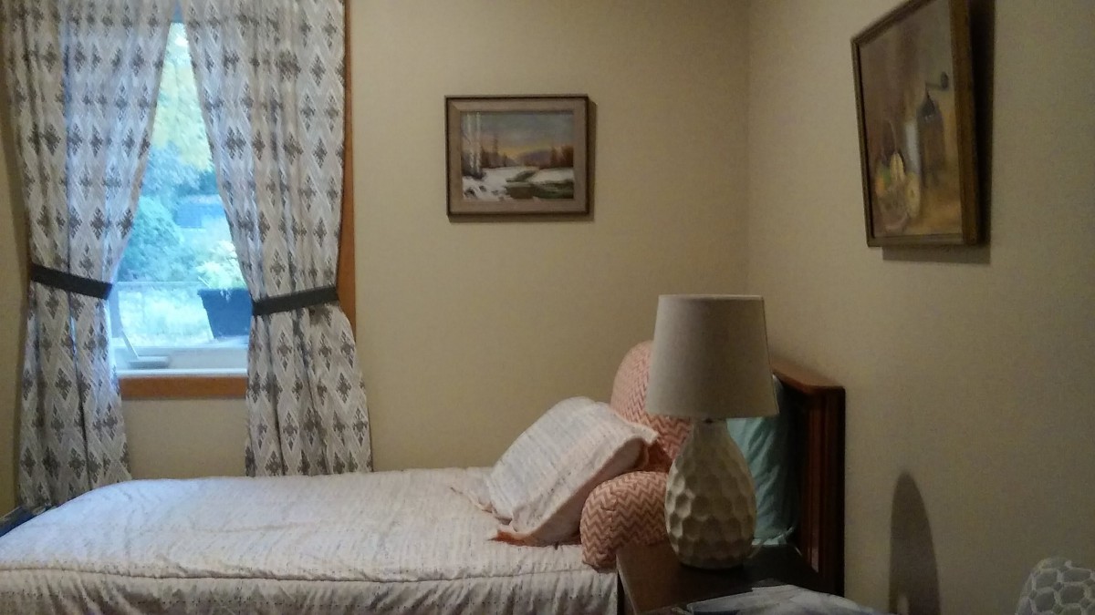 A cozy bedroom with a bed, lamp, and artwork on the wall.