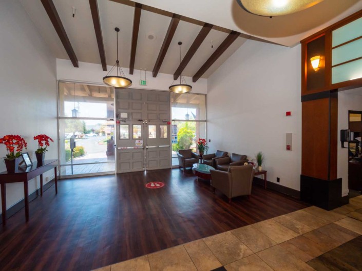 A modern lobby with wood flooring, stylish lighting, and a comfortable waiting area.