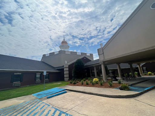 A view of a modern building surrounded by greenery under a partly cloudy sky.