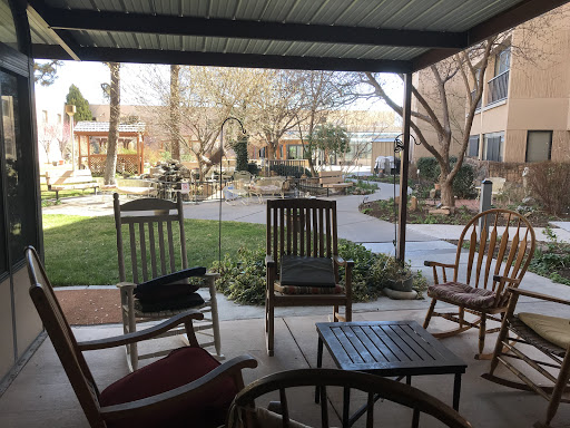 A serene outdoor patio area with rocking chairs and a view of a garden.