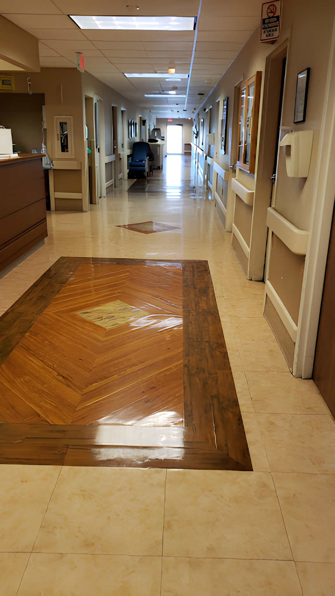 A well-lit hallway with an intricate floor design, likely in a hospital or similar facility.