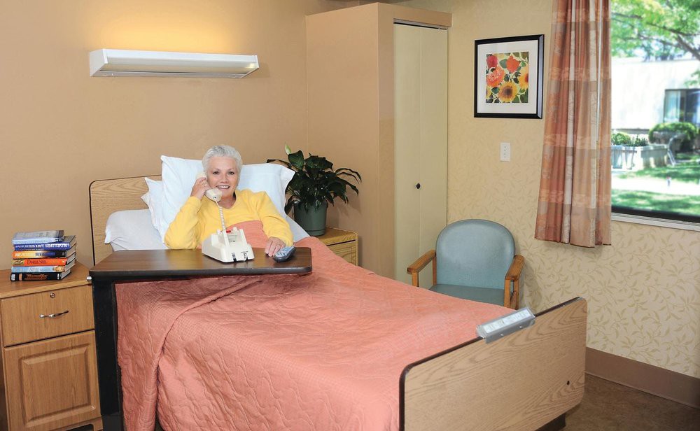 An elderly person resting in a hospital or nursing home room.