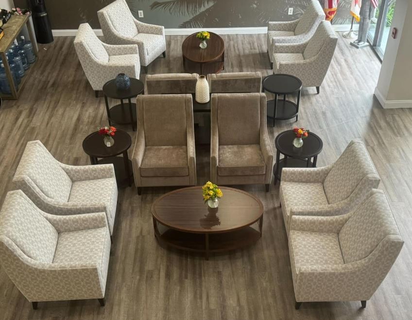 A neatly arranged seating area with chairs and coffee tables in a lobby or waiting room.