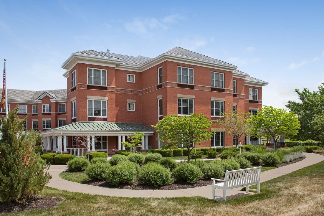 A brick residential building with well-maintained hedges and a walkway.